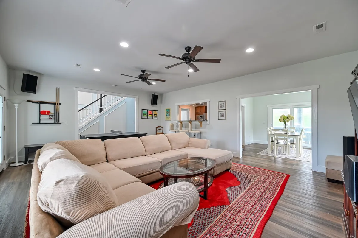 A large, comfortable living area with a sectional sofa, glass coffee table, red area rug, and an open floor plan. The space is designed for relaxing, movie nights, or hosting group activities, creating a welcoming atmosphere for families or friends traveling together.