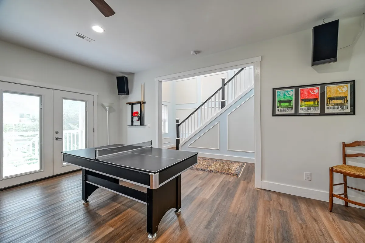 A playful recreation area featuring a ping pong table, staircase, and art-adorned wall. The mood is fun and relaxed, encouraging indoor entertainment and group bonding.