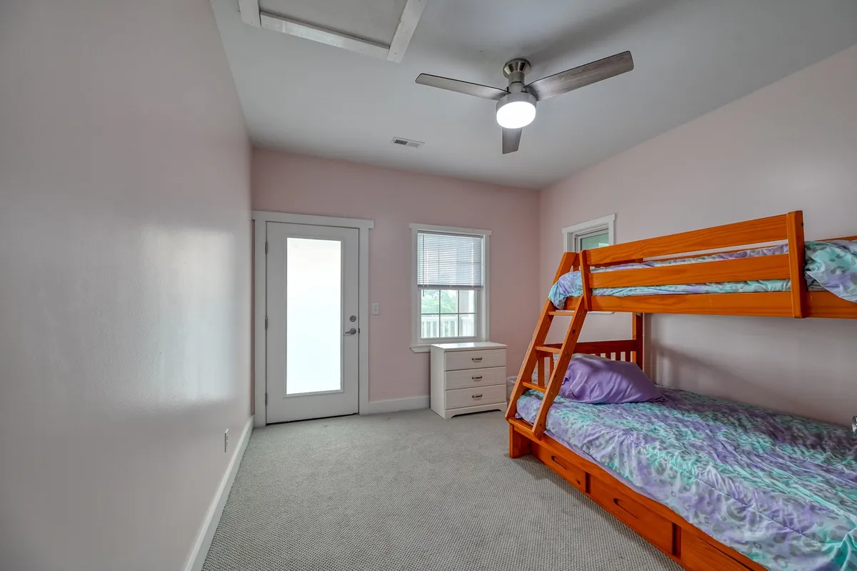 A cheerful bunkroom featuring a sturdy bunk bed, natural light streaming through windows, and an open door that hints at a welcoming, playful environment. The setup is ideal for kids or teens to enjoy sleepovers and downtime.