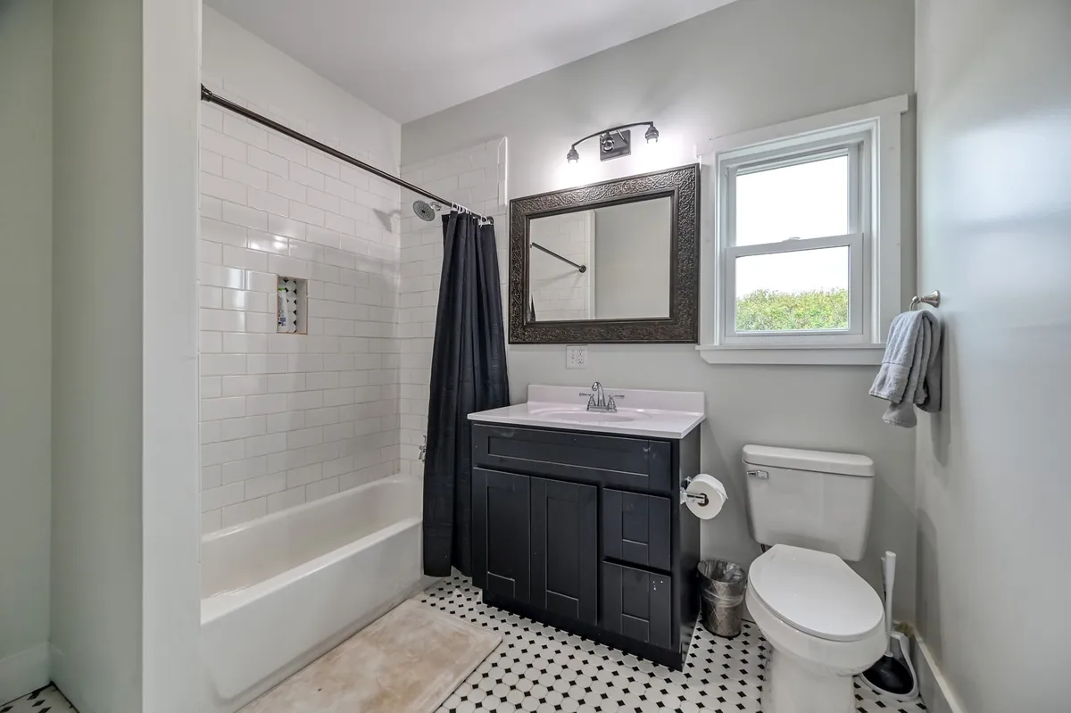 A modern, refreshing bathroom with a roomy shower, vanity with sink, and a mirror, all bathed in natural light from a nearby window. The clean, inviting setup promises comfort and convenience.